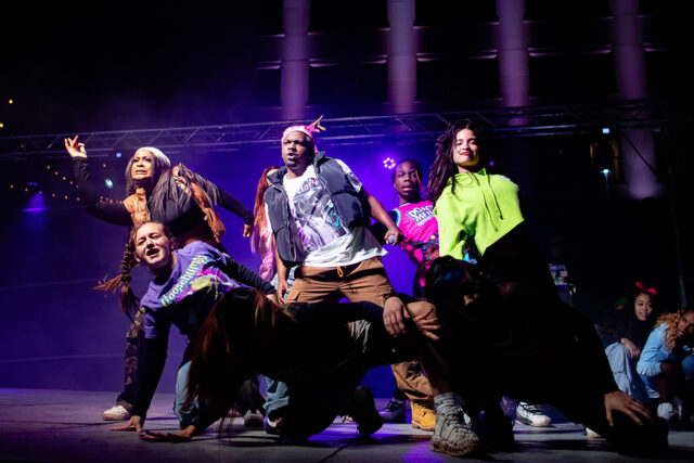 A photo of several people on stage during a dance performance