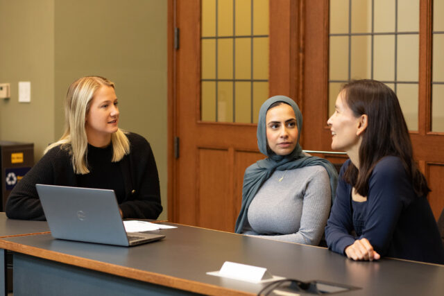 Photo of three women sitting at a table talking.