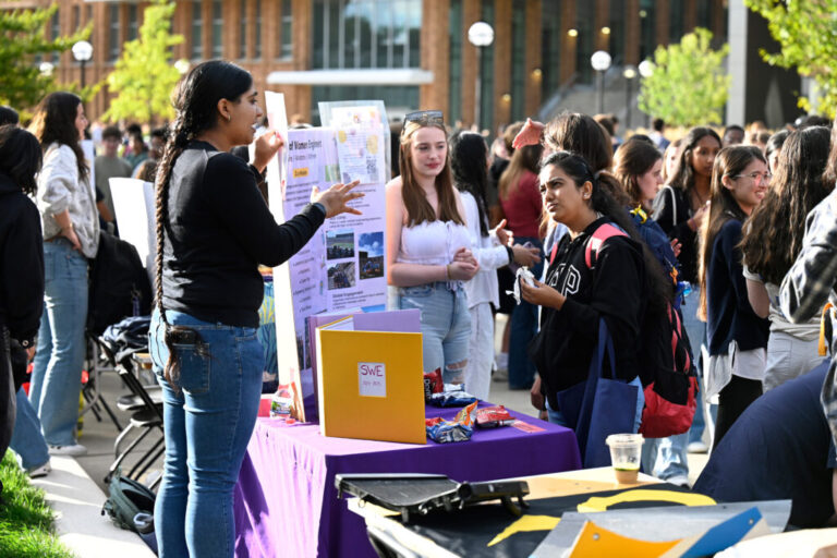 People standing around a table with posters and flyers.