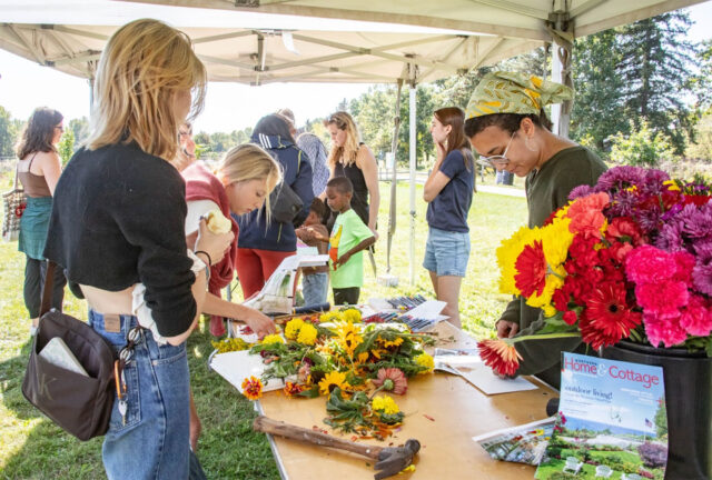 People stand around a table outside with flowers