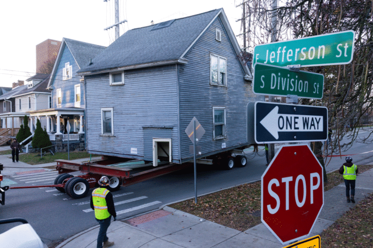 A house is hauled down a street by a trailer