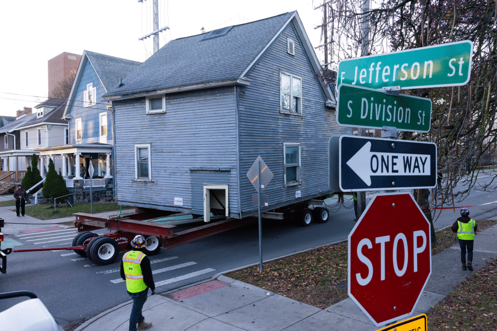 A house is hauled down a street by a trailer