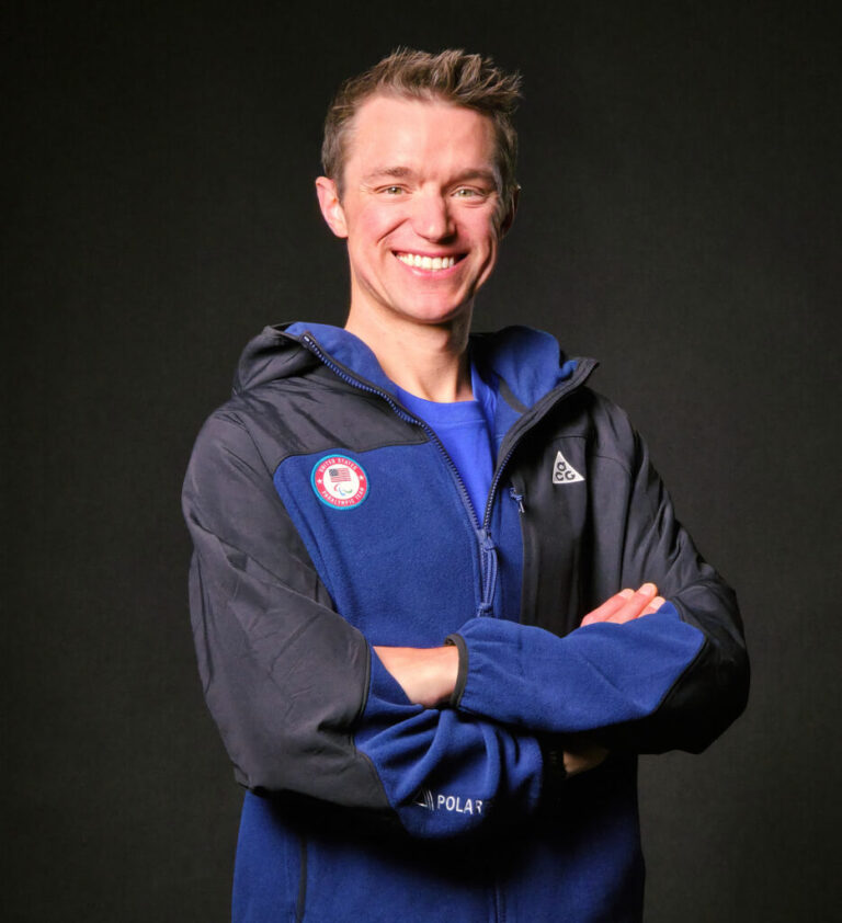 A man stands with his arms folded smiling