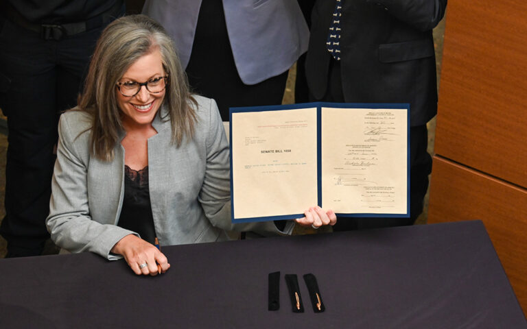 Gov. Katie Hobbs smiles holding a document.