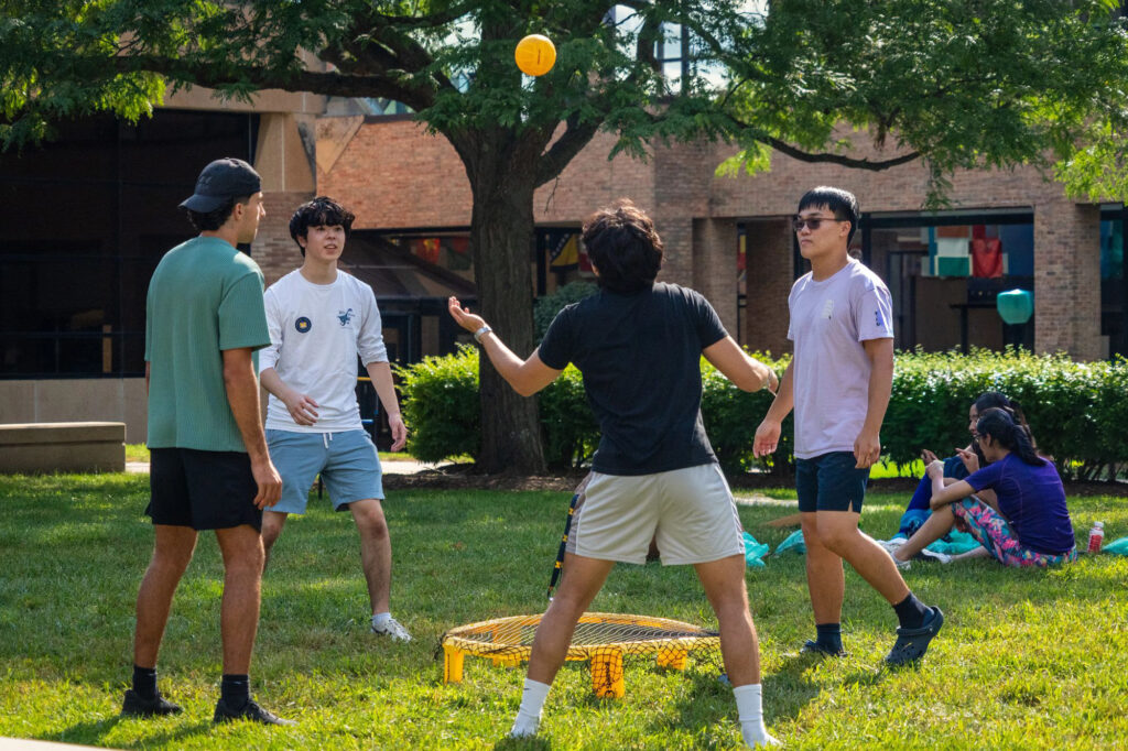 Four people play spike ball outside