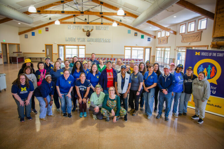 Dozens of people stand together for a photo inside a large building