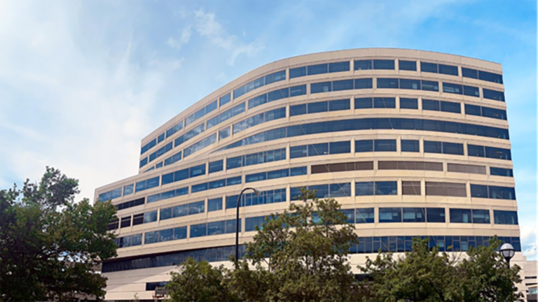 The exterior of a large hospital with blue sky and trees in the foreground