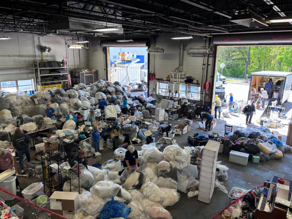 A room full of bags of clothing and other donations with people milling about