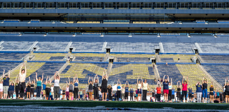 U-M employees doing yoga on the field in Michigan Stadium