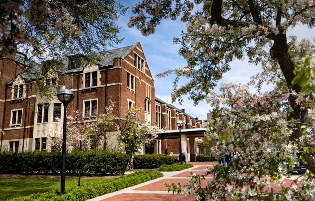 Photo of the Michigan League building with flowering trees in the foreground
